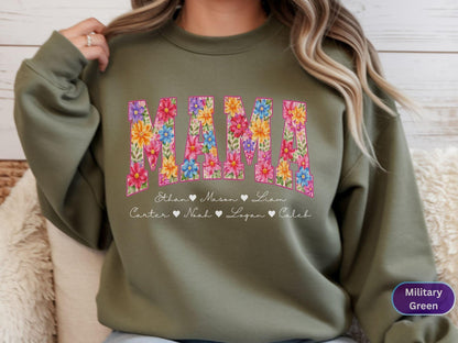 May include: Olive green sweatshirt with the word "MAMA" in large, floral-filled letters. Below the word are names with heart symbols. The sweatshirt is a comfortable, casual style.