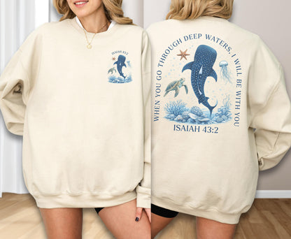 May include: Cream-colored sweatshirt with a marine-themed design. The front features a whale shark illustration and the text "Isaiah 43:2". The back displays a larger whale shark, turtle, and jellyfish with the text "When you go through deep waters, I will be with you. Isaiah 43:2".