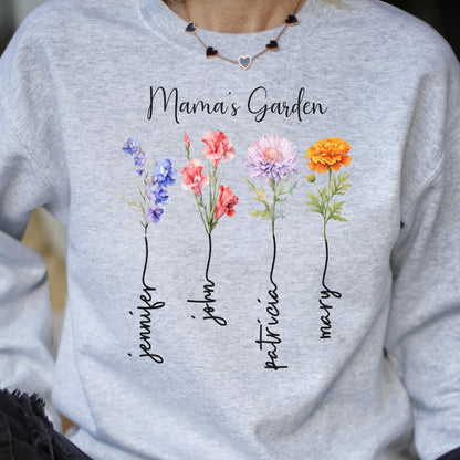 May include: A light gray sweatshirt with the text "Mama's Garden" and four colorful flower illustrations. Each flower has a name written below it: Jennifer, John, Patricia, and Mary. The flowers are blue, red, pink, and orange.