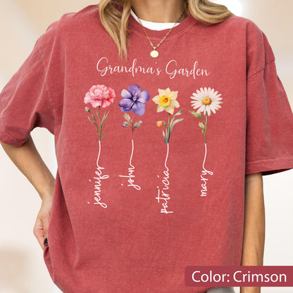 May include: Crimson-colored t-shirt featuring the text "Grandma's Garden" above four colorful flowers. Each flower has a name written below it: Jennifer, John, Patricia, and Mary. The shirt is a comfortable, casual style.