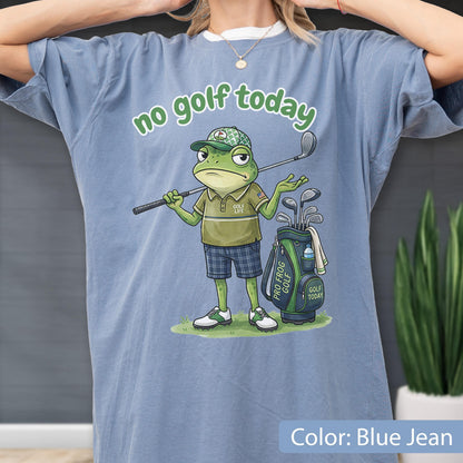 May include: Blue jean colored t-shirt featuring a cartoon frog golfer with the text "no golf today". The frog is wearing a golf hat, polo shirt, and plaid shorts, holding a golf club. A golf bag with clubs is next to the frog.