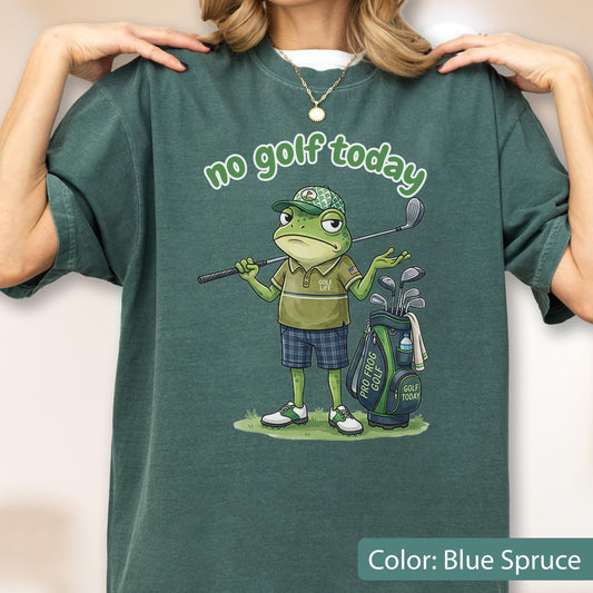 May include: Blue spruce t-shirt with a cartoon frog golfer. The frog wears a golf cap and plaid shorts, holding a golf club. Text above reads "no golf today." A golf bag with clubs is next to the frog.