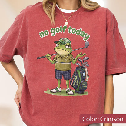 May include: Crimson-colored t-shirt with the text "no golf today." The shirt features a cartoon frog character wearing a golf hat and holding a golf club. A golf bag with clubs is next to the frog.