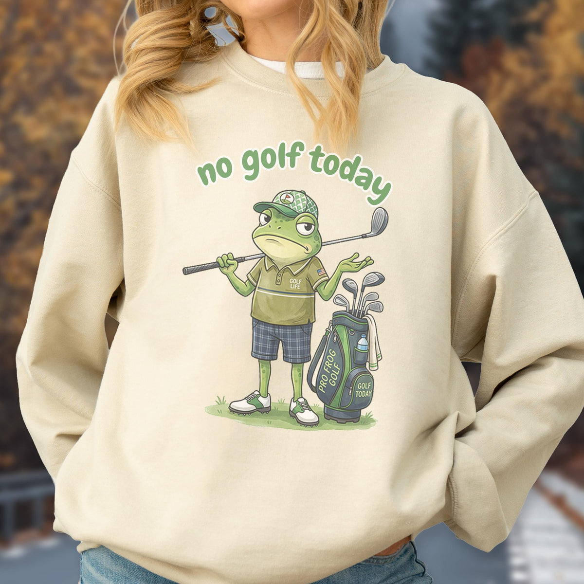 May include: Beige sweatshirt with the text "no golf today" in green. The graphic features a cartoon frog in a golf outfit, holding a golf club, with a golf bag and clubs. The frog is wearing a hat and shorts.