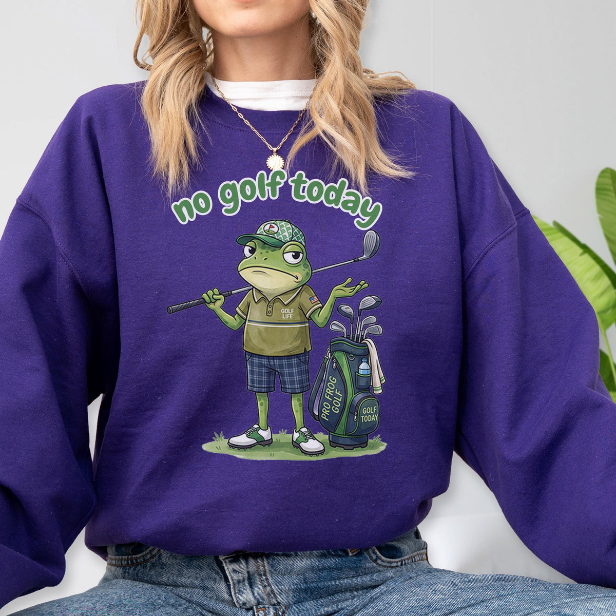 May include: A purple sweatshirt with the phrase "no golf today" in green script. The graphic features a cartoon frog in a golf outfit, holding a club and standing next to a golf bag. The golf bag has the words "Pro Frog Golf" on it.