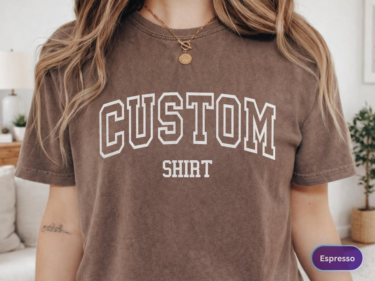 May include: Espresso-colored t-shirt with the text "CUSTOM SHIRT" in white, collegiate-style lettering. The shirt has a vintage, washed look.