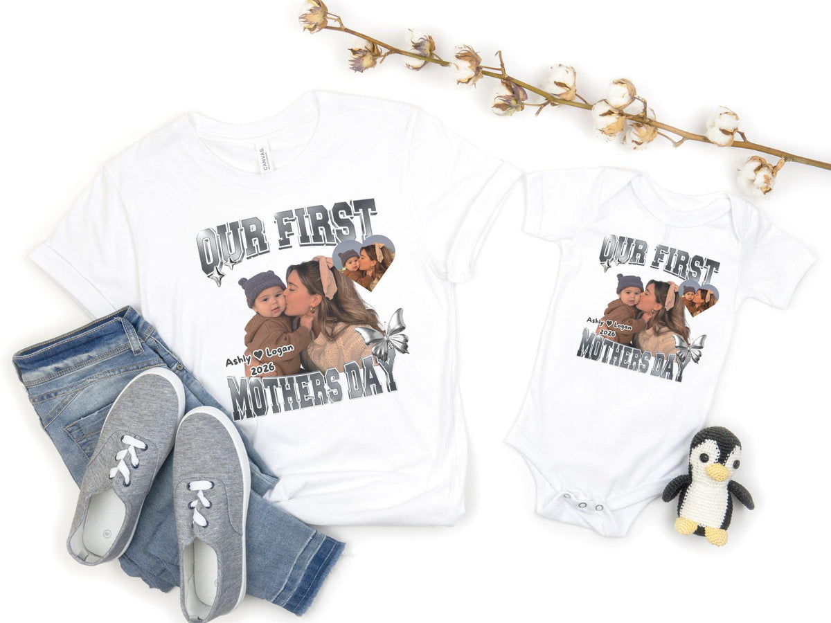 May include: White t-shirt and onesie set with a photo print and the text "OUR FIRST MOTHERS DAY". The photo shows a mother kissing a baby. The set includes a pair of gray sneakers and blue jeans.