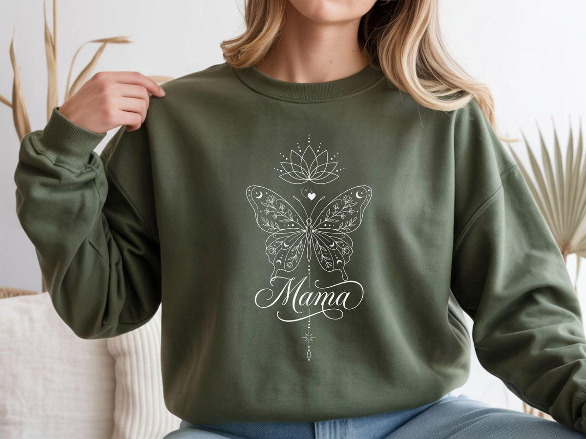 May include: Olive green sweatshirt with a white butterfly design, a lotus flower, and the word "Mama" in cursive script. The butterfly has intricate details and moon and star accents. A stylish and comfortable top.