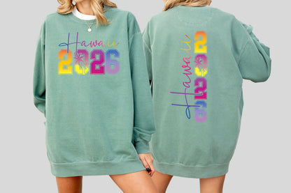 May include: A light green sweatshirt with the word "Hawaii" in a colorful script and the numbers "2026" in a gradient font. The back of the sweatshirt also features the word "Hawaii" and the numbers "2026" in a vertical arrangement.