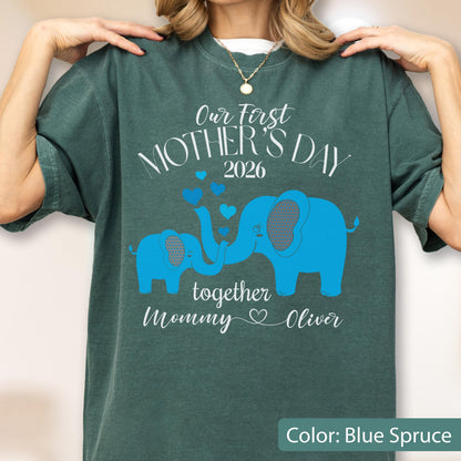 May include: Blue spruce t-shirt with the text "Our First Mother's Day 2026" and blue elephant graphics. The shirt also includes the words "together Mommy Oliver" in white script. The color is Blue Spruce.