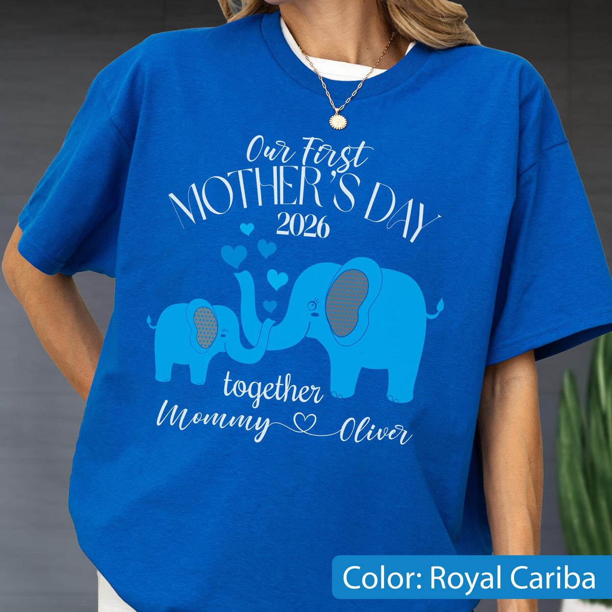 May include: Royal Cariba blue t-shirt with the text "Our First Mother's Day 2026" and two blue elephants. The elephants' trunks form a heart shape. The text "together Mommy Oliver" is also displayed.