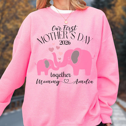 May include: Pink sweatshirt with the text "Our First Mother's Day 2026" and two pink elephants. The word "together" is below the elephants, and "Mommy Amelia" is written below that. Hearts are floating above the elephants.