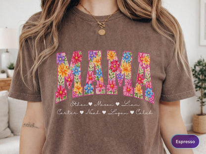 May include: Espresso-colored t-shirt with the word "MAMA" in large, floral-filled letters. Below the word are names with heart symbols. The shirt is a comfortable, casual style.