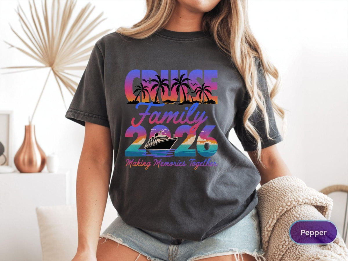 May include: Dark gray t-shirt with a colorful graphic that reads "Cruise Family 2026" with palm trees and a cruise ship. The text "Making Memories Together" is below the ship. The shirt is a casual style.