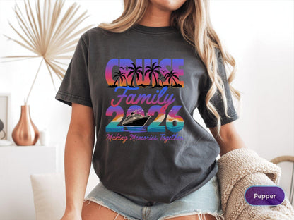 May include: Dark gray t-shirt with a colorful graphic that reads "Cruise Family 2026" with palm trees and a cruise ship. The text "Making Memories Together" is below the ship. The shirt is a casual style.