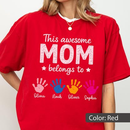 May include: Red t-shirt with the text "This awesome MOM belongs to" and four colorful handprints below. The names Olivia, Noah, Oliver, and Sophia are printed under each handprint. The shirt also has the text "Color: Red".