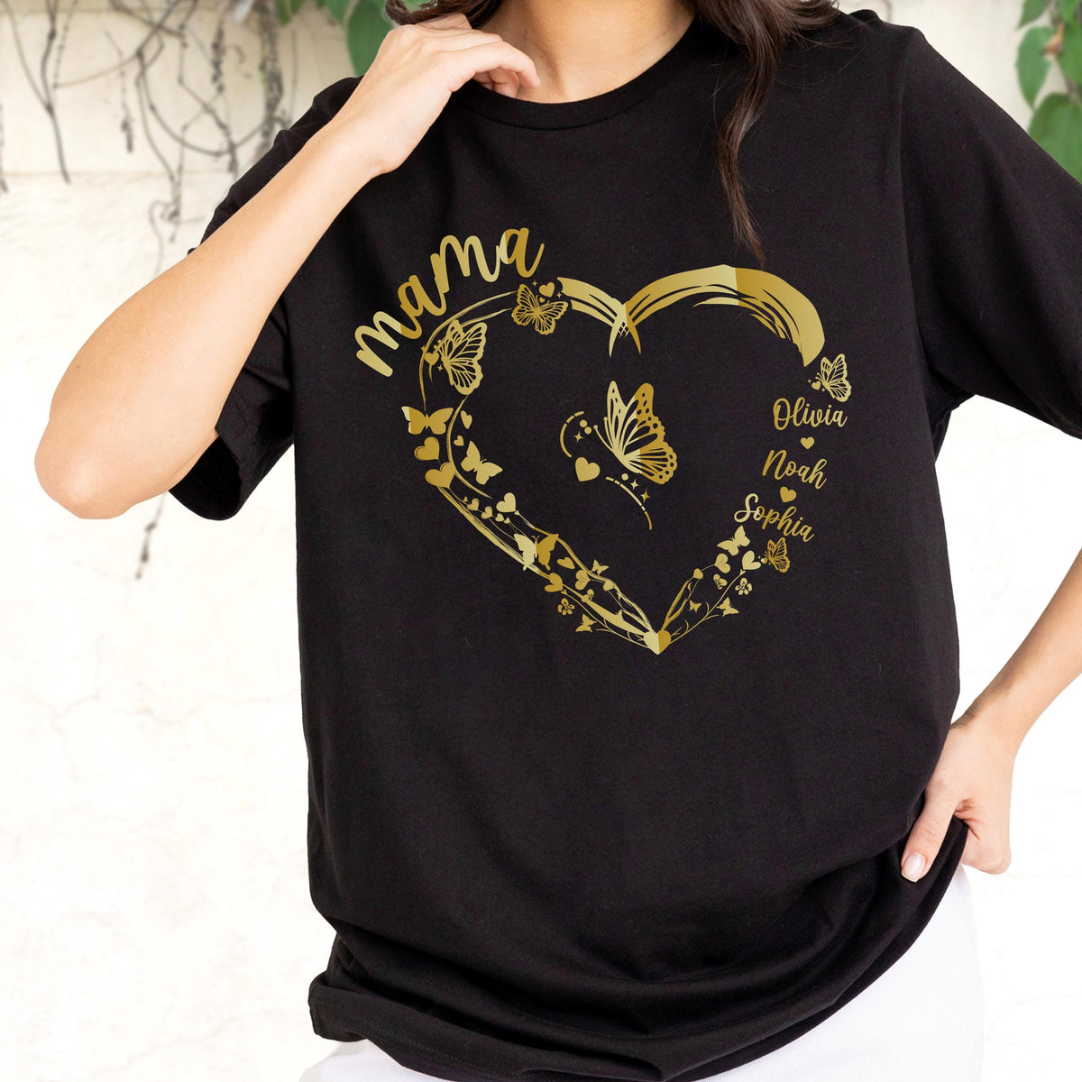 May include: Black t-shirt with a gold heart design. The heart is filled with butterflies and the word "mama" is above it. The names Olivia, Noah, and Sophia are printed inside the heart.