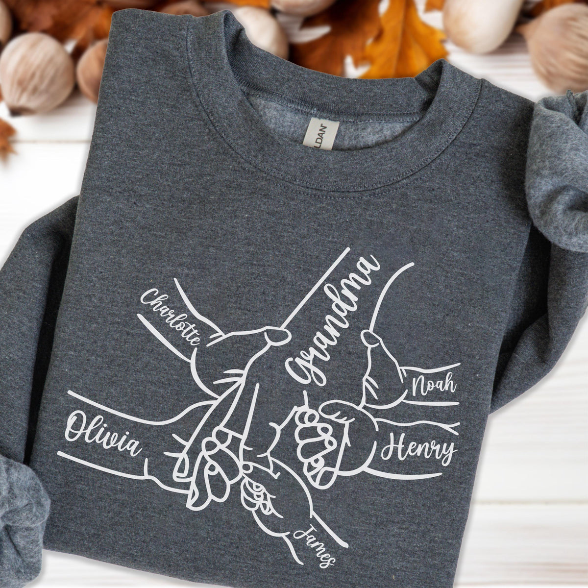 May include: Dark gray sweatshirt with a white graphic of hands holding each other, with the word "Grandma" and the names "Olivia", "Charlotte", "Noah", "Henry", and "James" printed on it.