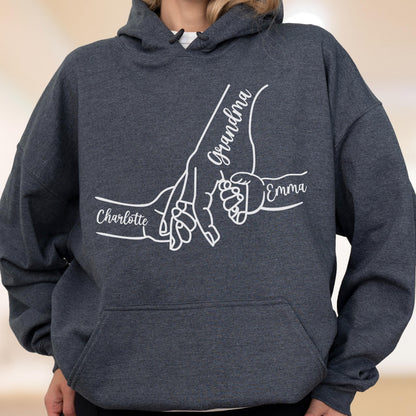 May include: Dark gray hoodie with a white graphic of three hands holding each other. The word "Grandma" is written on one hand, and the names "Charlotte" and "Emma" are written on the other hands.
