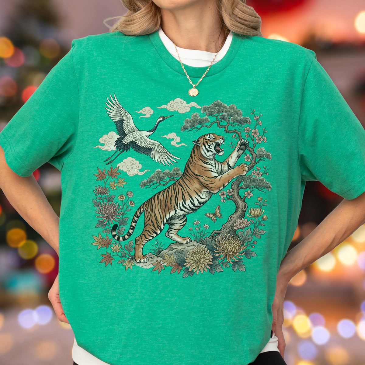 May include: Green t-shirt featuring a detailed illustration of a tiger, crane, and floral elements. The tiger is depicted in a dynamic pose, with a crane in flight above. The design incorporates traditional Asian art motifs, creating a vibrant and eye-catching graphic.
