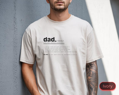 May include: Ivory-colored t-shirt with the word "dad" and its definition printed in black. The definition includes numbered points and the phrase "See also". The shirt is a relaxed fit.