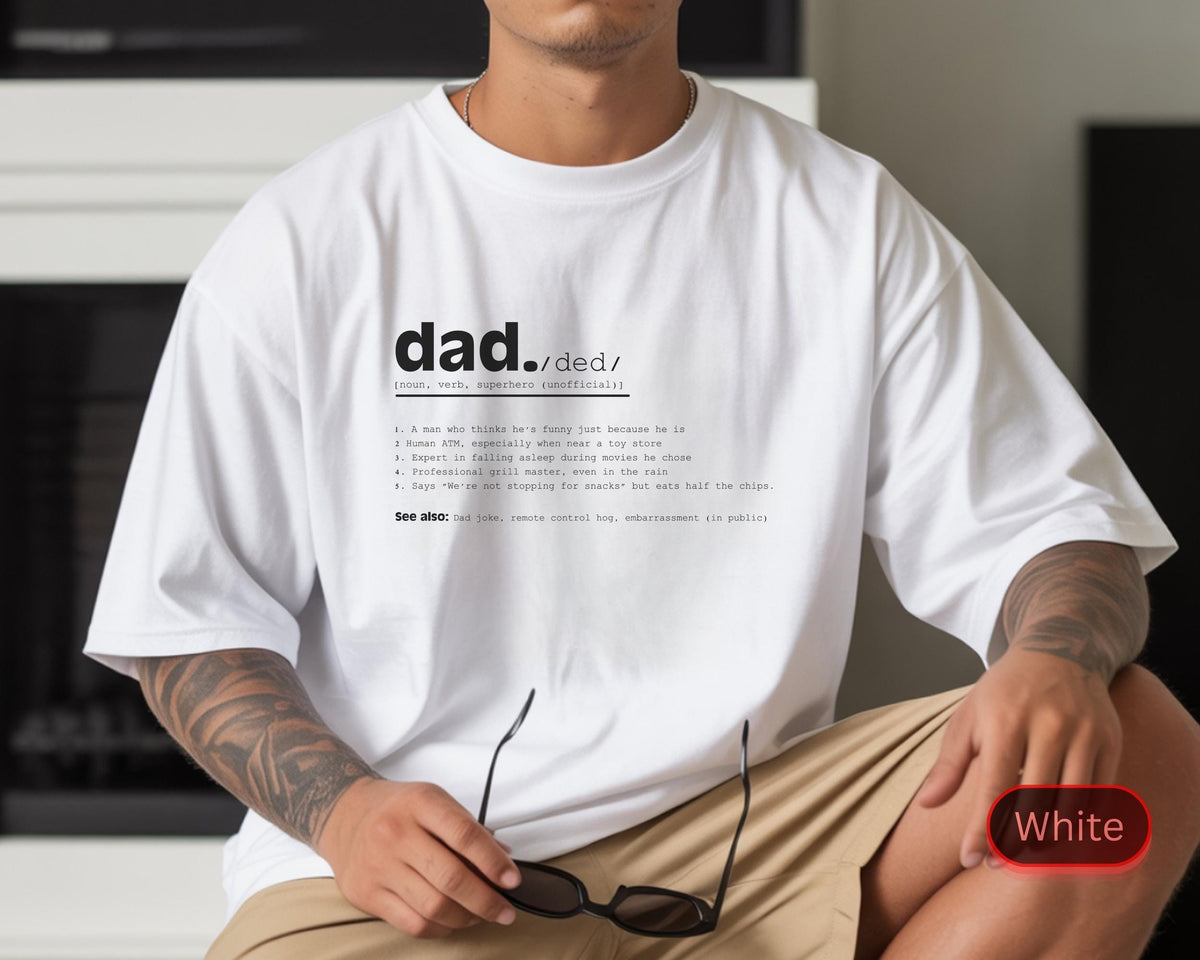 May include: White t-shirt with the word "dad" and its definition printed in black. The definition includes humorous descriptions. The shirt is a casual style, with short sleeves and a relaxed fit. The model is wearing khaki shorts.