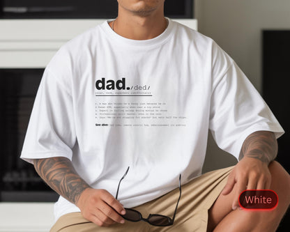 May include: White t-shirt with the word "dad" and its definition printed in black. The definition includes humorous descriptions. The shirt is a casual style, with short sleeves and a relaxed fit. The model is wearing khaki shorts.