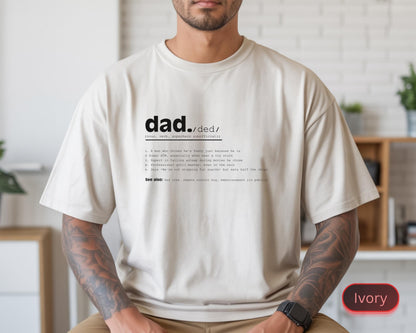 May include: Ivory-colored t-shirt with the word "dad" and its phonetic pronunciation printed in black. Below the word, a definition of "dad" is printed in a smaller font. The shirt is a relaxed fit.