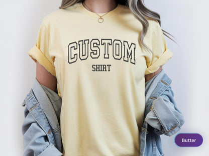 May include: Butter yellow t-shirt with the word "CUSTOM" above "SHIRT" in a black, collegiate-style font. The shirt has rolled-up sleeves and is paired with a light blue denim jacket.