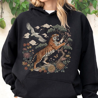 May include: Black hoodie featuring a detailed illustration of a tiger, crane, and floral elements. The tiger is orange and black, set against a backdrop of clouds and flowers. The design has an Asian-inspired aesthetic.