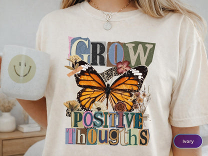 May include: Ivory-colored t-shirt featuring a large butterfly graphic with orange, black, and white wings. The words "GROW" and "POSITIVE THOUGHTS" are printed above and below the butterfly in a collage style.
