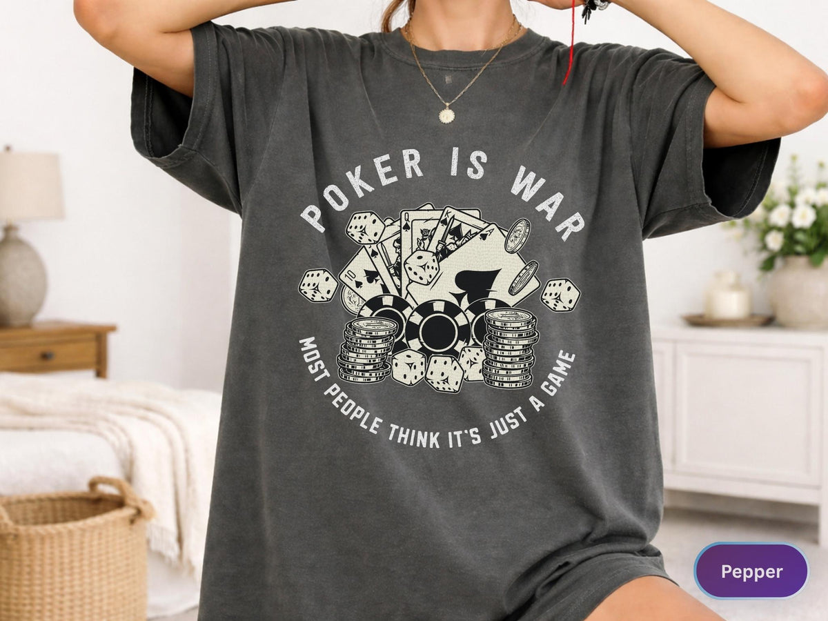 May include: Dark gray t-shirt with the text "POKER IS WAR" and a graphic of poker chips, playing cards, and dice. The text "MOST PEOPLE THINK IT'S JUST A GAME" is also printed on the shirt.
