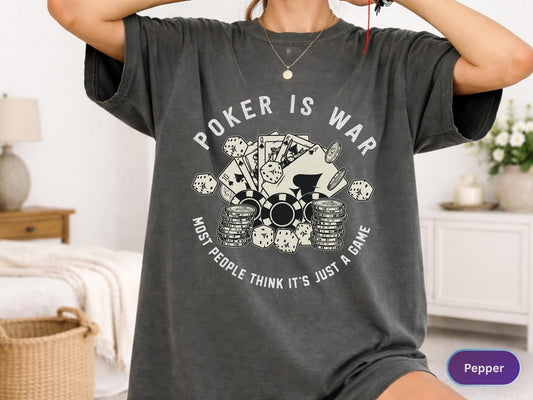 May include: Dark gray t-shirt with the text "POKER IS WAR" and a graphic of poker chips, playing cards, and dice. The text "MOST PEOPLE THINK IT'S JUST A GAME" is also printed on the shirt.