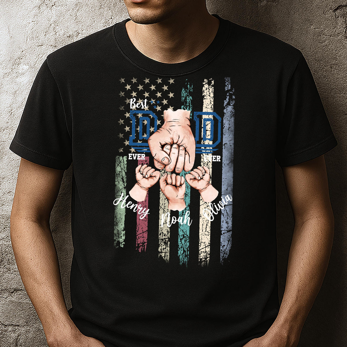 May include: Black t-shirt with a distressed American flag design. The flag has the words "Best Dad Ever" and "Dad" in blue letters. The flag is surrounded by three hands holding each other, with the names "Henry", "Noah", and "Olivia" written below.