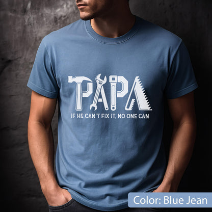 May include: Blue jean-colored t-shirt with the word "PAPA" in white, incorporating tool graphics. Below, the text reads "IF HE CAN'T FIX IT, NO ONE CAN". The shirt is a crew neck style.