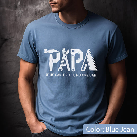 May include: Blue jean-colored t-shirt with the word "PAPA" in white, incorporating tool graphics. Below, the text reads "IF HE CAN'T FIX IT, NO ONE CAN". The shirt is a crew neck style.