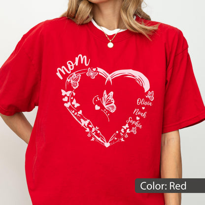 May include: Red t-shirt with a white heart-shaped design, butterflies, and the word "mom". The names "Olivia", "Noah", and "Sophia" are also printed on the shirt. The shirt's color is red.