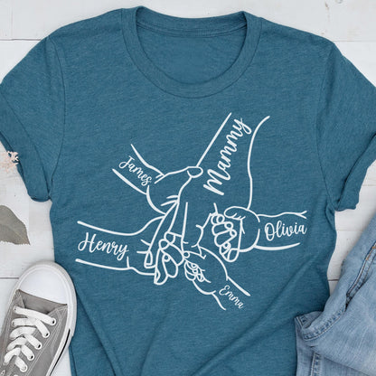 May include: Teal t-shirt with a white graphic of hands holding each other, with the names "James", "Henry", "Olivia", "Emma", and "Mammy" written on the hands. The shirt is made of a soft material.