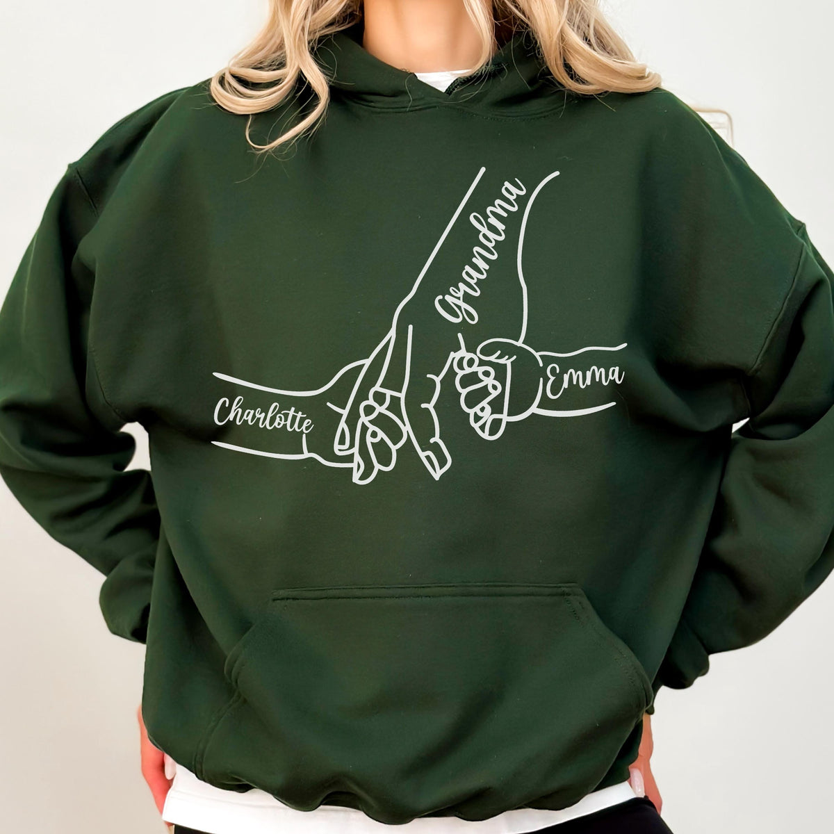May include: Dark green hoodie with a white graphic of three hands holding each other. The word "Grandma" is written in cursive, with the names "Charlotte" and "Emma" also displayed.