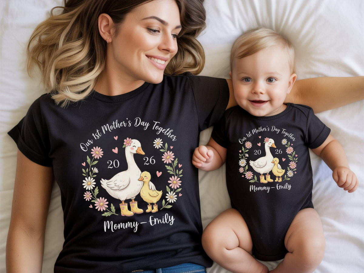 May include: Matching black t-shirts and onesie with a floral wreath design featuring a goose and duckling, the text "Our 1st Mother's Day Together 2026 Mommy-Emily". Perfect for Mother's Day.