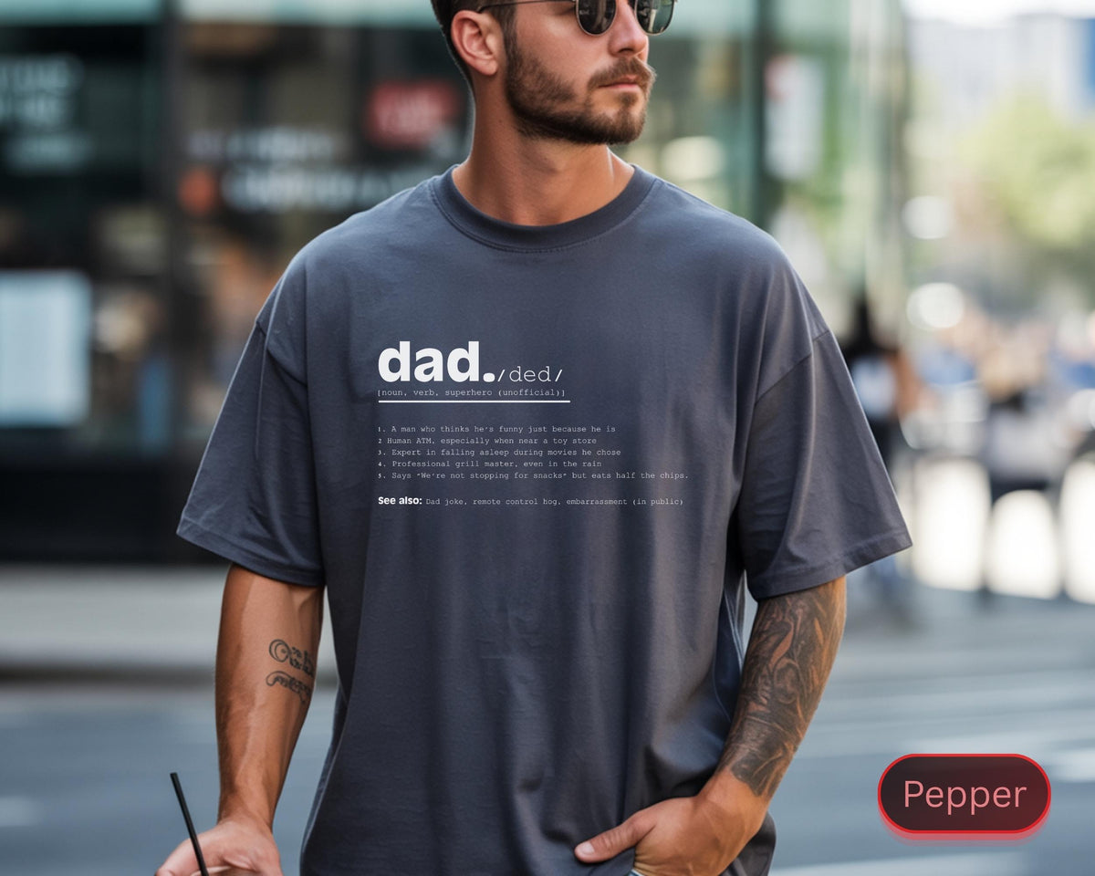 May include: A dark gray t-shirt with the definition of "dad" printed in white. The definition includes a list of characteristics. The shirt is a relaxed fit and has short sleeves.