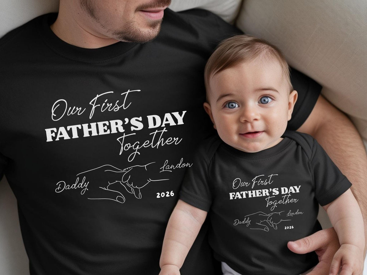 May include: Black matching t-shirts and baby bodysuit with the text "Our First Father's Day Together" and the name "Landon" and the year "2026". The adult is wearing a t-shirt, and the baby is wearing a bodysuit.