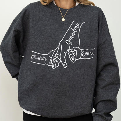 May include: Dark gray sweatshirt with a white graphic of three hands holding each other. The word "Grandma" is written in cursive, with the names "Charlotte" and "Emma" also displayed in white.