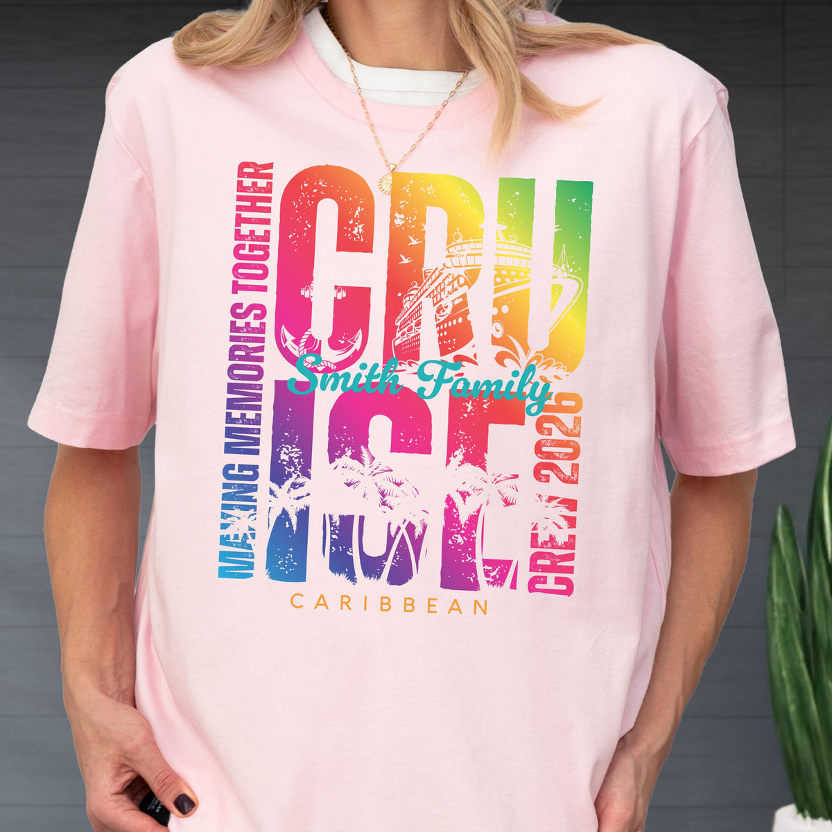 May include: A light pink t-shirt with a colorful graphic that says "CRUISE" in large letters, with the words "MAKING MEMORIES TOGETHER", "Smith Family", "CREW 2026", and "CARIBBEAN" also printed on the shirt. The shirt has short sleeves.