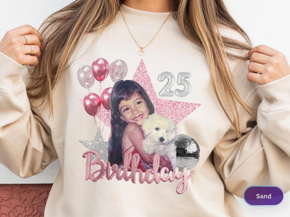 May include: A sand-colored crewneck sweatshirt featuring a graphic print of a young girl holding a white puppy. The design includes pink balloons, a glittery pink star, a silver star, a silver disco ball, the number 25, and the word Birthday.