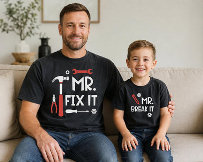 May include: Two black short-sleeved t-shirts. The larger shirt features a red hammer, wrench, pliers, screwdriver, and the white text 'MR. FIX IT'. The smaller shirt features a red pencil and the white text 'MR. BREAK IT' with small white nut icons.