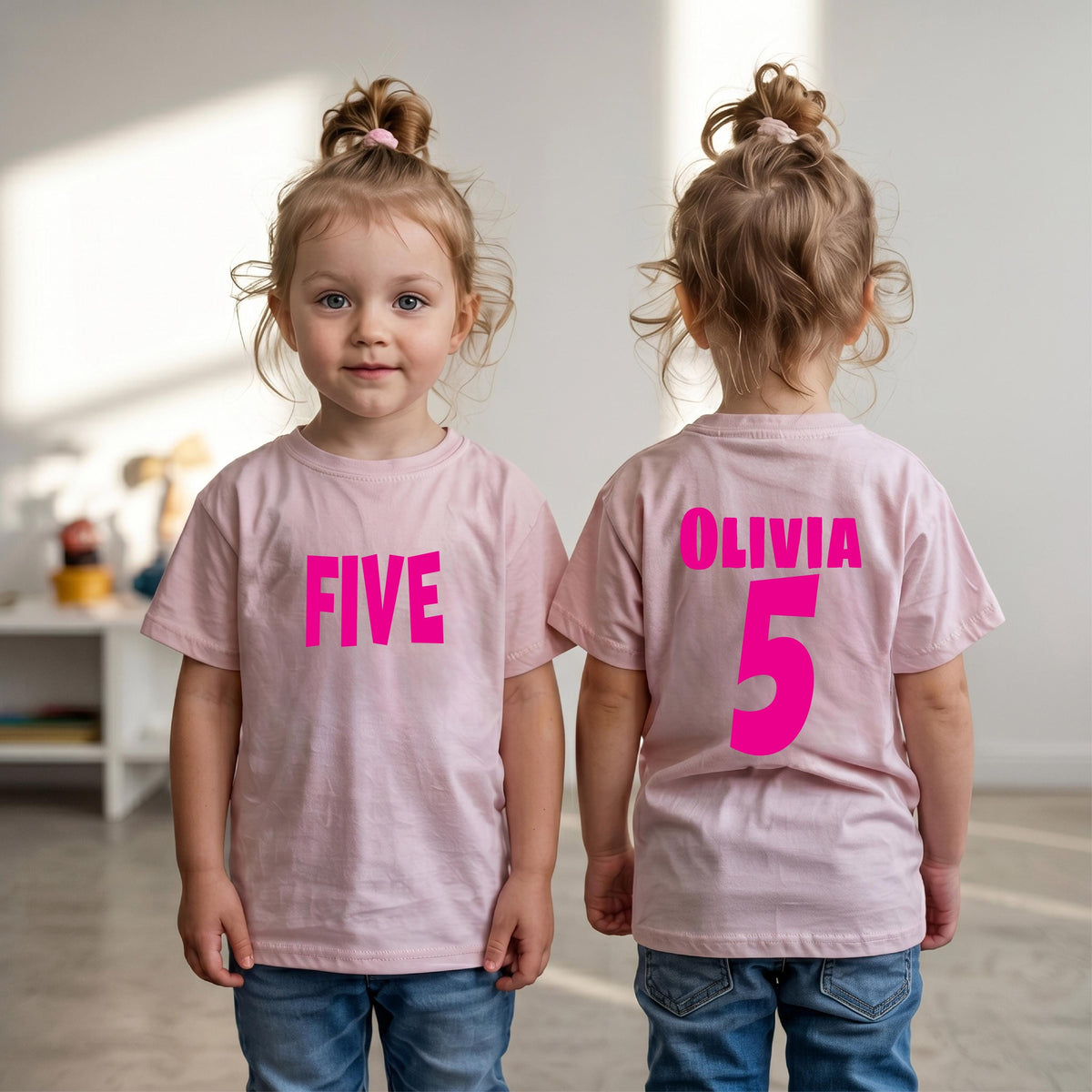 May include: A light pink t-shirt featuring the word FIVE in bright pink lettering on the front, and the name OLIVIA with the number 5 in bright pink lettering on the back, paired with blue denim jeans.