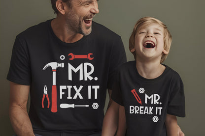 May include: Two black short-sleeved t-shirts. The larger shirt features a red hammer, wrench, pliers, screwdriver, and the white text "MR. FIX IT". The smaller shirt features a red pencil, nuts, and the white text "MR. BREAK IT" in a bold font.