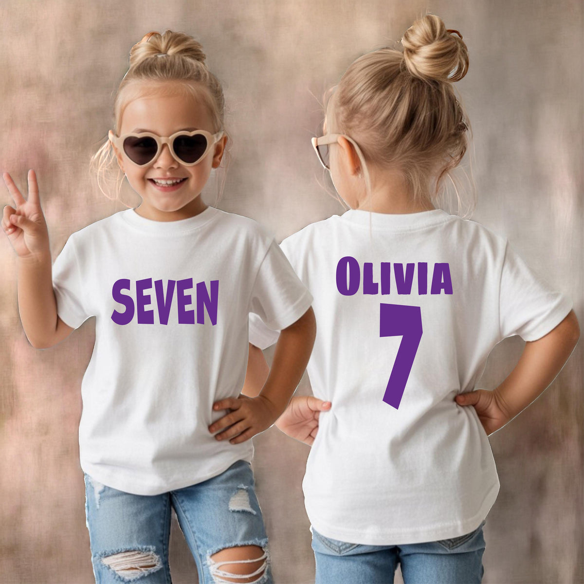May include: A white short-sleeved t-shirt featuring the purple text SEVEN on the front and the purple text OLIVIA with the number 7 on the back. The shirt is paired with light blue distressed denim jeans and heart-shaped sunglasses.