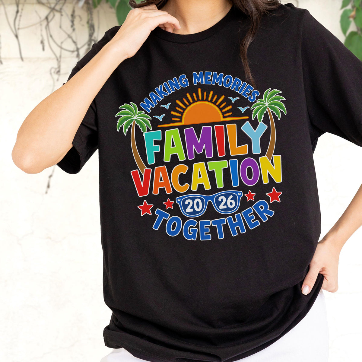 May include: A black t-shirt featuring a colorful graphic with the text "MAKING MEMORIES FAMILY VACATION TOGETHER 20 26". The design includes a yellow sun, green palm trees, blue sunglasses, and red stars, all arranged in a circular pattern.